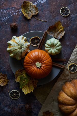Pumpkin on a plate. Autumn cozy background with leaves, vanilla. Dark background Copy space Top viewの写真素材