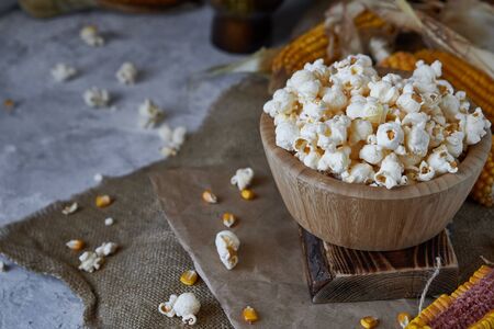 Traditional popcorn in a wooden bowl and corncobs on the table. Rustic country style Copy spaceの写真素材