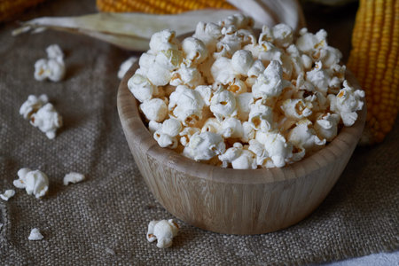 Traditional popcorn in a wooden bowl and corncobs on the table. Rustic country style