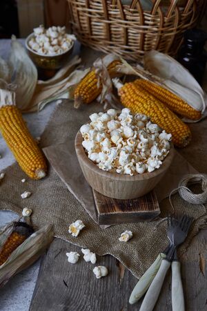 Traditional popcorn in a wooden bowl and corncobs on the table. Rustic country styleの写真素材