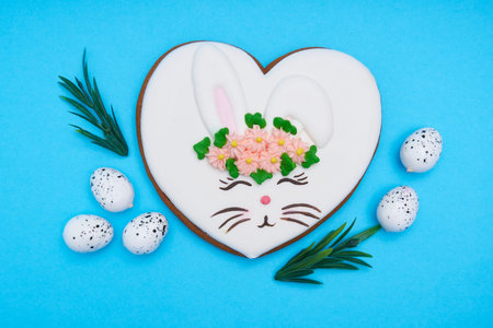 Easter bunny, gingerbread with glaze with quail eggs on blue background Copy space Top view