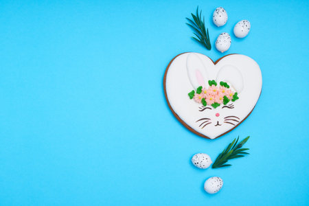 Easter bunny, gingerbread with glaze with quail eggs on blue background Copy space Top view