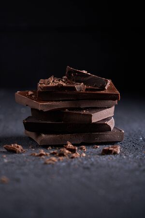 Piece of dark chocolate and chocolate chips on a dark background Vertical Dark tableの写真素材