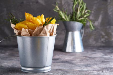 Fried potatoes country style. Barbecue potatoes. In a metallic bowl on a gray background Copy space