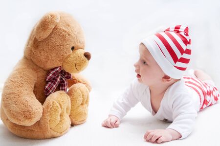 Cute baby in santa costume and big teddy bear. New Year and Christmas cardの写真素材