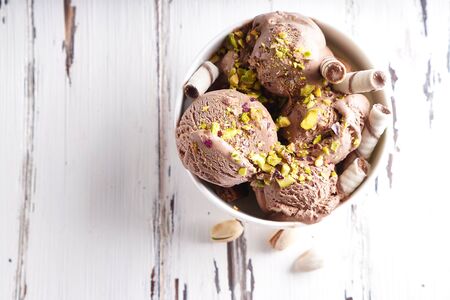 Chocolate ice cream balls with pistachio and cookies in a white bowlの写真素材