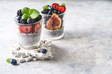 Healthy chia pudding with strawberries, blackberries, blueberries and figs served in a glass on light backgroundの写真素材