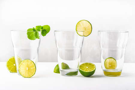Drink glasses with water, lime, mint and ice on white background Close upの写真素材