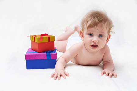 Cute smiling baby boy with gift box on light backgroundの写真素材