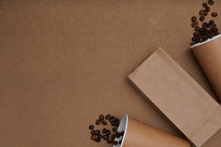 Two disposable craft glasses with package and coffee beans on craft background . Monochrome photo...