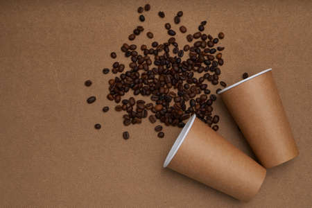 Two disposable craft glasses with coffee beans on craft background . Monochrome photoの写真素材