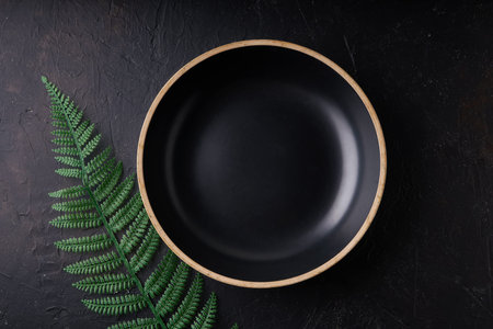 Black stone bowl with palm leaves on a black background Copy space Dark photo Mockup
