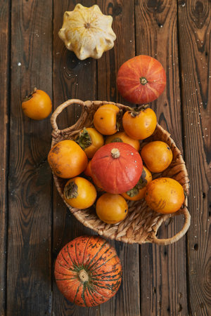 basket with a harvest of persimmons and pumpkins on a wooden table. Country style Food background