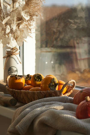 basket with a harvest of persimmons on the windowの写真素材