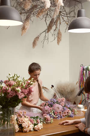 young woman florist in her studio makes a beautiful bouquet. Working moments Selective focusの写真素材