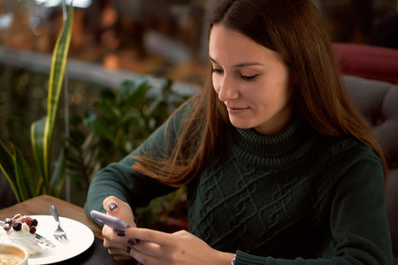 Young brunette woman in medical mask in cafe with laptop