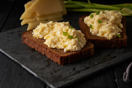 Scrambled eggs with green onion with gluten free bread on black tableの写真素材