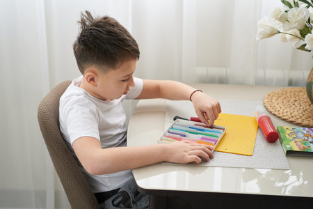 little boy sculpts figures from plasticine, sitting at home at the table. He is passionate about his...