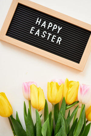 bouquet of spring tulips and board with the inscription Happy Easter. Festive spring concept