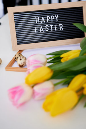 bouquet of spring tulips, quail eggs and board with the inscription Happy Easter. Festive spring...