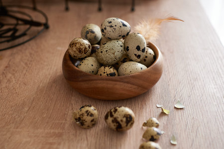 quail eggs in a wooden bowl painted with a feather on a wooden table. Easter concept copy space