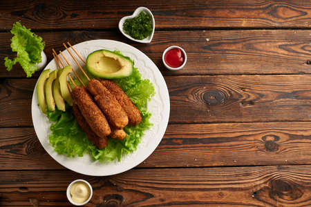 Tasty corn dog with sauce and salad served on white plate on wooden tableの写真素材