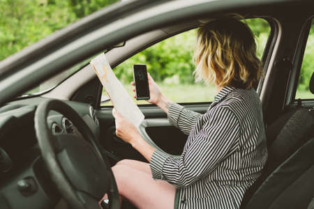 Happy young woman travels by car on the road.の写真素材
