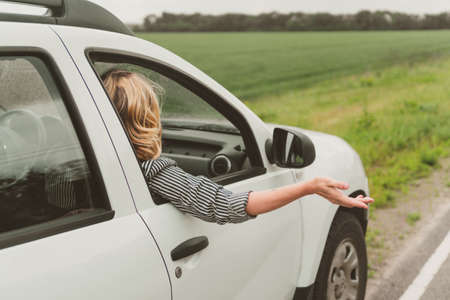 Happy young woman travels by car on the road.の写真素材