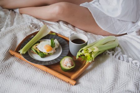 beautiful girl with a white towel on her head sits in the bed and is going to have breakfast