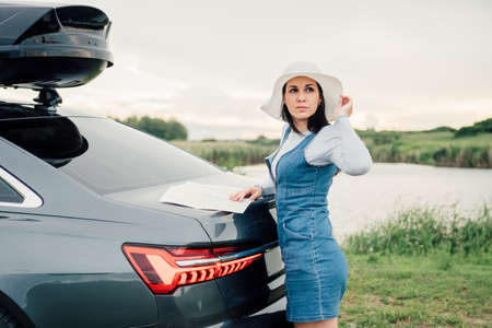 Beautiful young woman travels by car, leaning out the window and having fun.の写真素材