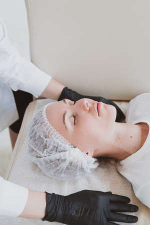 Beautician masseur doing facial massage to young womanの写真素材