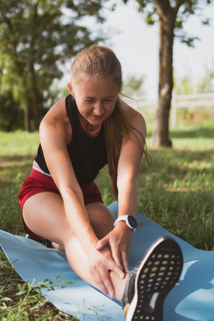 beautiful sportive woman with long hair doing stretching in the park before jogging
