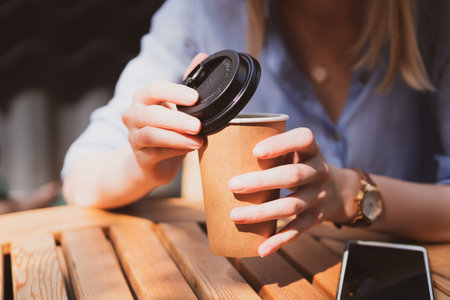 young charming woman drinking coffee in a street cafe in summer