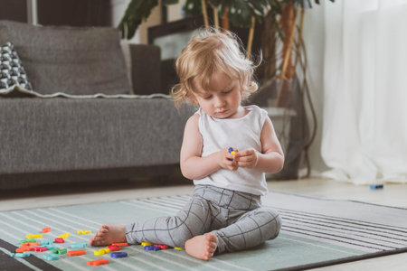 little cute toddler playing with toy letters sitting on the floor