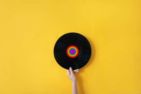 Female hand holding a plate with LGBT symbol on a yellow background Concept photoの写真素材