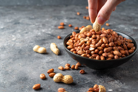Raw Peanuts in small wooden bowl on natural gray rustic desk.