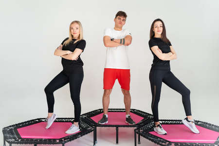 Three adorable fitness people In sportswear jumping on sport trampoline White backgroundの写真素材