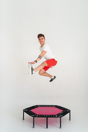 Strong fitness man In sportswear jumping on sport trampolineの写真素材