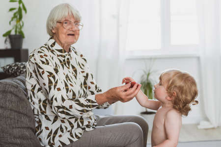 Elderly woman treats her little grandson to strawberriesの写真素材