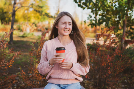 Portrait of charming young woman with long hair and in casual style communicates on phone and taking...