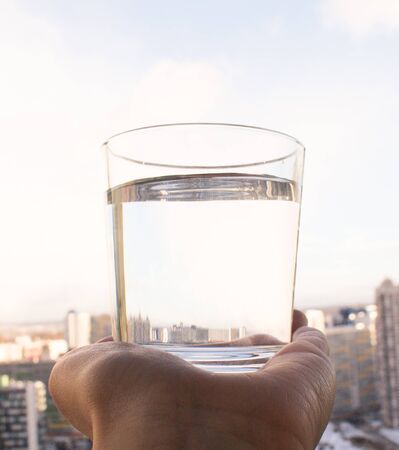 a clean glass of water in hand on blue sky backgroundの写真素材