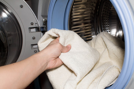 hand putting linen into washing machineの写真素材