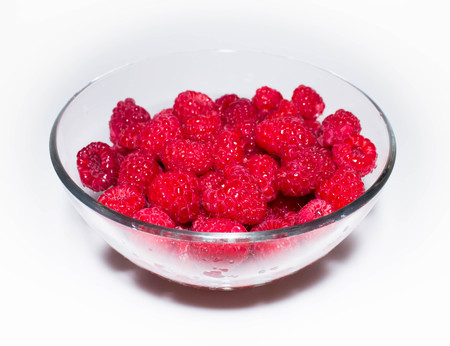 Juicy red raspberry in a transparent glass bowlの写真素材