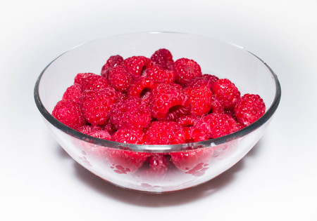 Fresh juicy red raspberry in a transparent glass bowlの写真素材