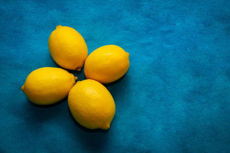 four yellow lemons on a bright blue backgroundの写真素材