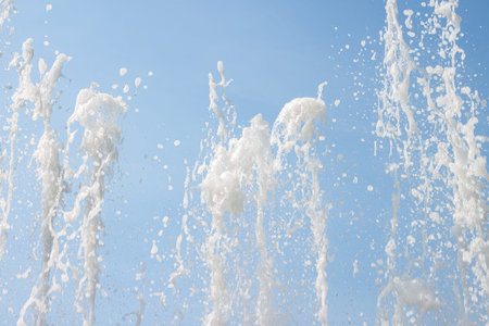 Flowing fountain water jets spray pattern and texture with blue sky background cool macro wallpaper
