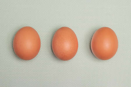 Three uncooked brown eggs with light blue backgroundの写真素材