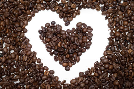 Coffee beans on white background with heart shape in center macroの写真素材