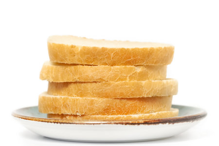 Sliced fresh baguette bread loaf with plate isolated white background