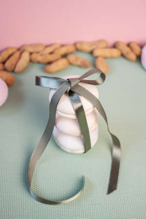 Stack of three marshmallows with green ribbon, bow and almond nuts macro on light blue backgroundの写真素材